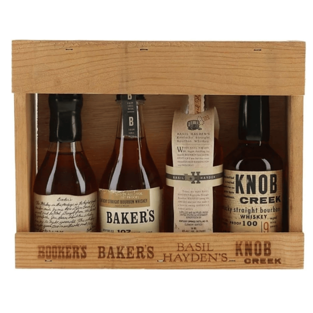 A wooden gift box containing four whiskey bottles: Booker's, Baker's, Basil Hayden's, and Knob Creek. The bottles are arranged side-by-side inside a light-colored wooden crate with the brand names of the bottles printed on the front.